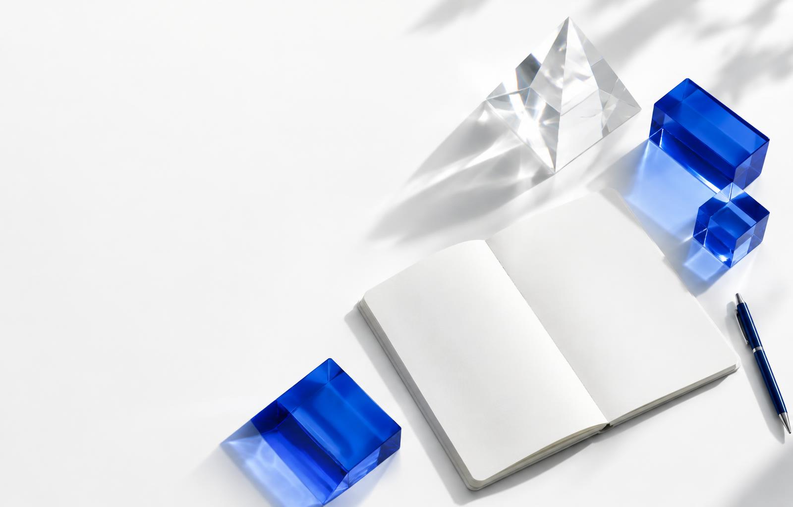 Mesa criativa com caderno e esculturas de vidro azul
